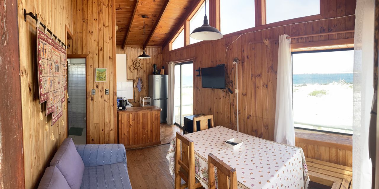 Interior de la cabaña: living, comedor y cocina revestidos en madera